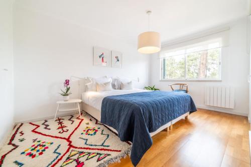 a white bedroom with a bed and a rug at Apartment Aroeira Golf II in Carcereiro