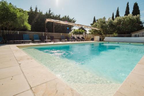 a swimming pool with blue chairs in a yard at Logis Hotel des Granges in Arles