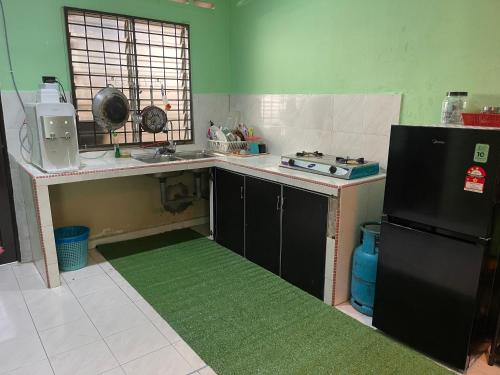 a kitchen with a sink and a refrigerator at Homestay Taman Delima Paka in Kampong Gong Gemia