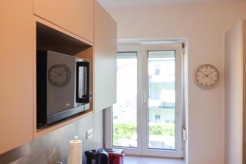 a kitchen with a tv and two clocks on the wall at Apartment Passau D, Zentral, Cozy, Parking Place in Passau