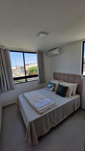a bedroom with a large bed with two windows at Apartment in Praia de Formosa in Cabedelo