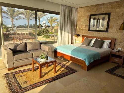 a bedroom with a bed and a living room with a couch at Chateau Cabana Resort in Jbeil