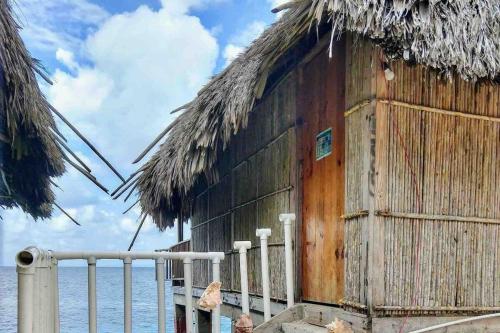 a wooden building with a thatched roof next to the water at Cabins over the sea on Narasgandub in Isla Wichitupo Grande