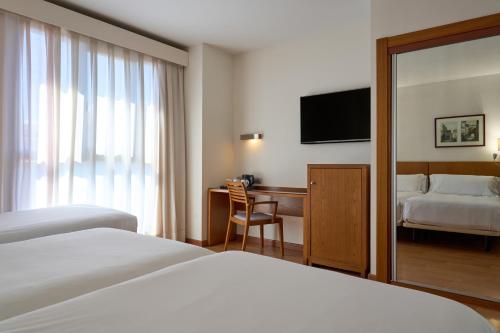 a hotel room with two beds and a desk and a television at Senator Granada in Granada