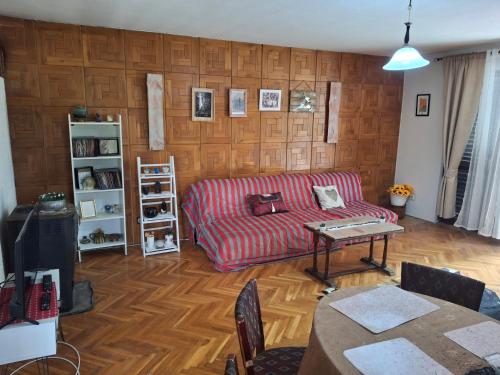 a living room with a red couch and a wooden wall at Avalski put in Grkova