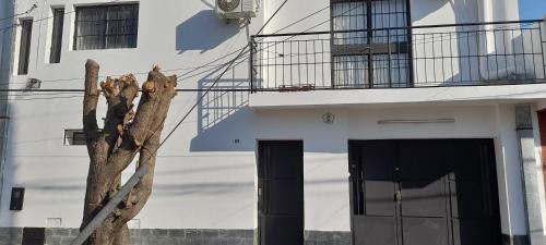 een boom naast een wit gebouw met een deur bij Amador Lucero apart II in San Miguel de Tucumán