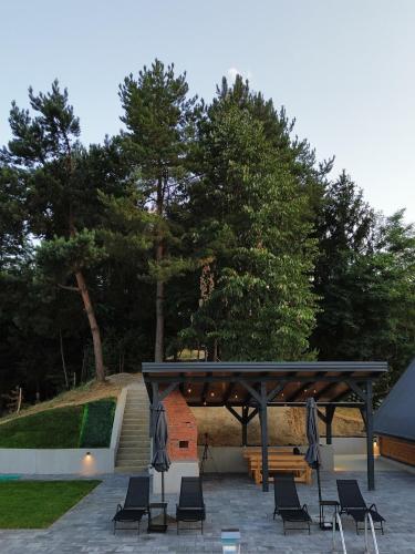a pavilion with chairs and a bench and trees at Nale Luxury Chalet in Bratunac