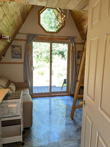 ein winziges Haus mit einem großen Fenster und einer Treppe in der Unterkunft Tree Ring Cabin on 33 Acres in Powell River
