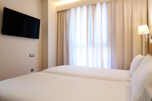 a hotel room with two beds and a television at Senator Granada in Granada