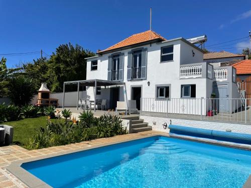 a villa with a swimming pool in front of a house at Tranquilidade in Estreito da Calheta