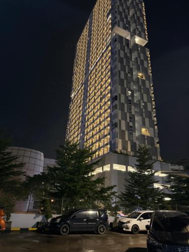 a tall building with cars parked in a parking lot at Citra Plaza Nagoya City View in Kangboi