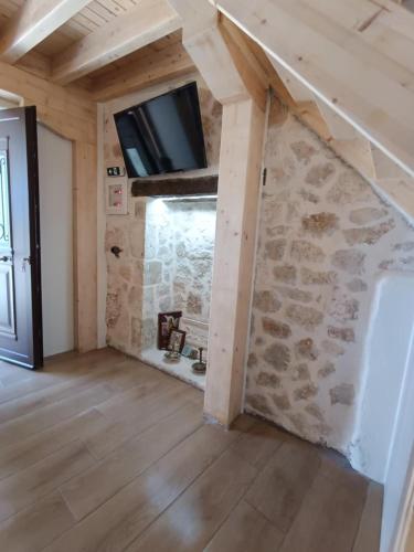 a room with a stone wall with a tv on the wall at Maniaveta's House in Exanthia