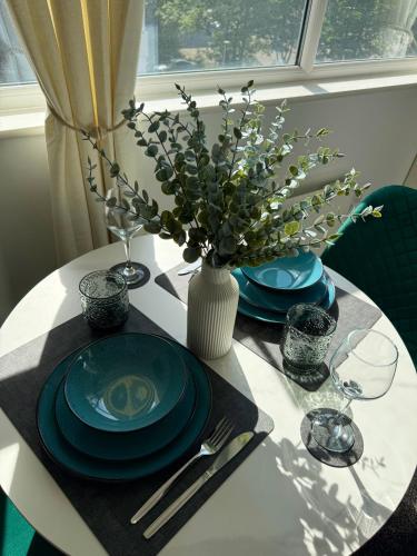 a table with plates and a vase of flowers on it at Zelena Luxurious Apartment, Private Parking, Fast Wi-Fi, Self Check-In Anytime Perfect For Late Arrivals, 5 Minutes to Old Trafford Stadium in Manchester