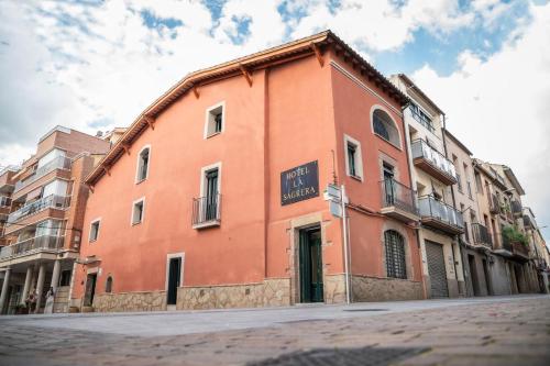a large orange building on the side of a street at Hotel La Sagrera in Sant Fruitos de Bages