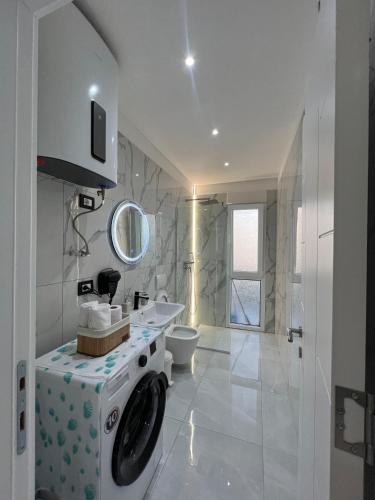 a white bathroom with a washing machine in it at RbNb Shengjin in Shëngjin