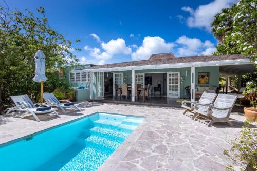 a swimming pool in front of a house with chairs at Piscadera Bay Resort 79 in Willemstad