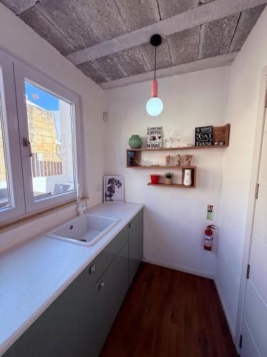a kitchen with a sink and a window at Il-Maxtura - Charming 17th Century House Of Character in the Historical Three Cities in Cospicua