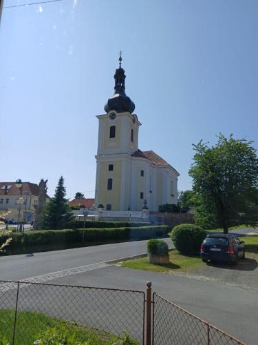 a white building with a clock tower on a street at Apartman Barrington in Žinkovy