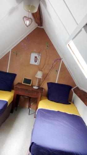 une chambre mansardée avec deux lits et une table dans l'établissement au petit bonheur, à Putanges