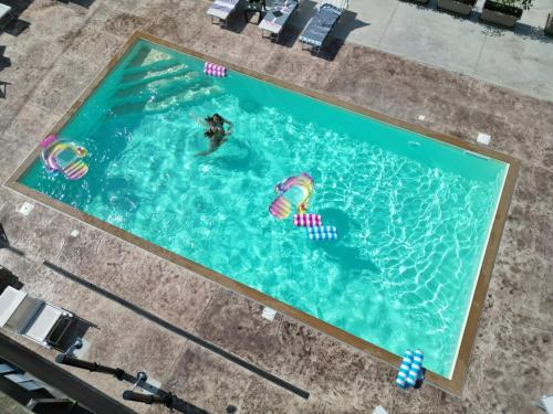 an overhead view of two people swimming in a swimming pool at Coast To Coast - Rooms & Pool! Camere moderne e piscina in Sant'Egidio del Monte Albino