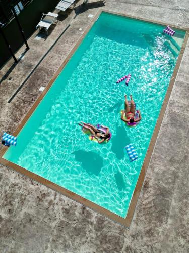 a pool with two people in the water at Coast To Coast - Rooms & Pool! Camere moderne e piscina in Sant'Egidio del Monte Albino