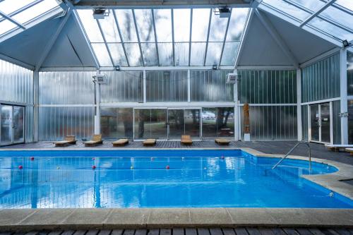 an indoor swimming pool with a glass ceiling at Pioneros Suites by Grupo Tierra Gaucha in San Carlos de Bariloche