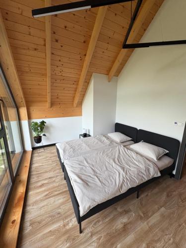a large bed in a room with a wooden ceiling at Sielskie Chatki - domki Twardorzeczka Lipowa in Plebańska