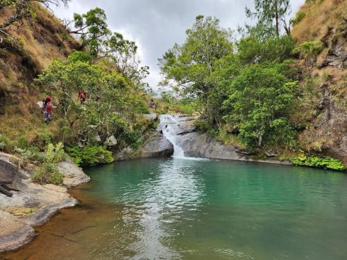 a river with a waterfall and people walking in the water at Mulanje Vista House in Mulanje