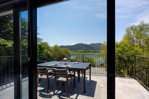 a table and chairs on a balcony with a view of a lake at Lake House Buric in Vranjina