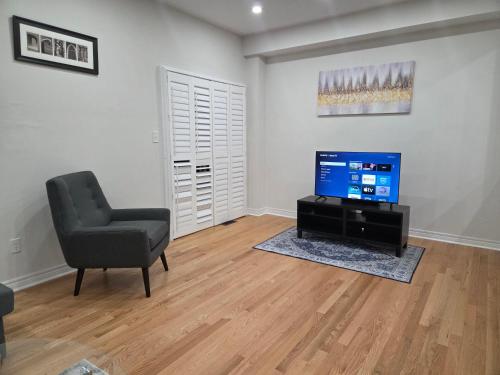 a living room with a chair and a television at Four Bedroom Spacious House with Parking in Milton, Ontario in Milton