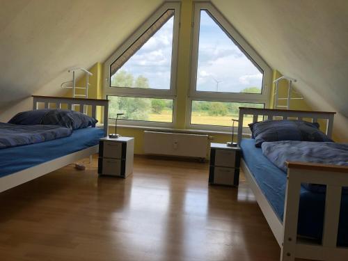 two beds in a room with two large windows at Monteur- und Ferienwohnung BeKi in Kamp-Lintfort