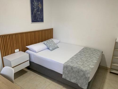 a small bedroom with a bed with a night stand at Hotel Garden House Guaviare in San José del Guaviare