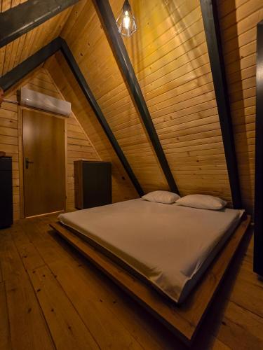 a bed in a wooden room with a wooden floor at Nale Luxury Chalet in Bratunac
