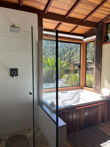 a large bathroom with a tub and a window at Chalé Vale da Gavéa in Resende