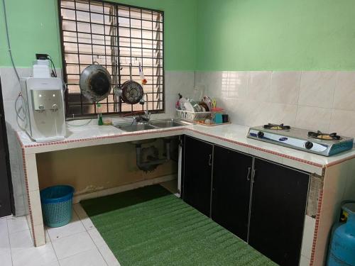 a small kitchen with a sink and a stove at Homestay Taman Delima Paka in Kampong Gong Gemia