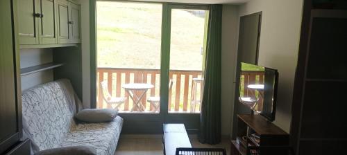 un salon avec un canapé et une grande fenêtre dans l'établissement appartement La Plagne Montalbert, à La Celle-sous-Gouzon