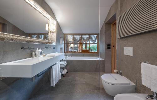 a bathroom with two sinks and a tub and a toilet at Auberge de La Maison in Courmayeur