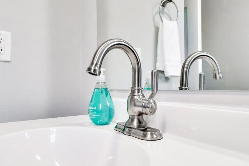 un lavandino del bagno con una bottiglia di sapone blu dentro di Extended Stay! The Sunny Cottage at Byrd Park! a Richmond