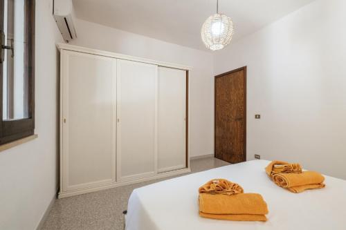 a bedroom with white cabinets and two towels on a bed at Villa Vinci in Campu Longu