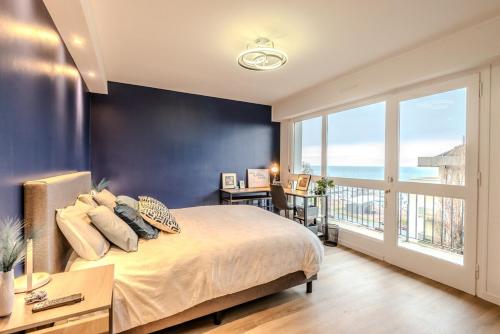 une chambre avec un grand lit et une grande fenêtre dans l'établissement À quelques pas du Lac Leman, à Évian-les-Bains