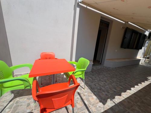 a red table and green chairs outside a building at Villa Bebi in Sarandë