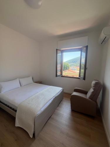 a bedroom with a bed and a chair and a window at La Terrazza di Paola in Il Romito