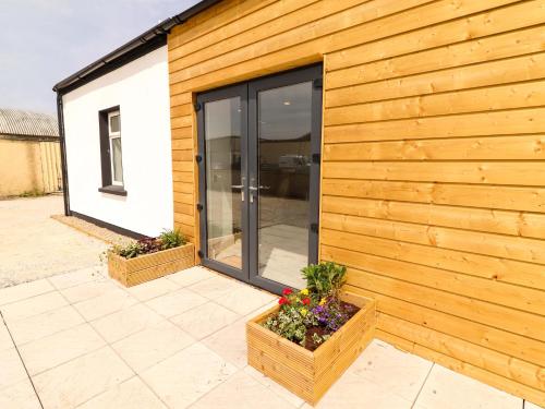 a building with sliding glass doors and flowers on a patio at Teach Ti in Miltown Malbay