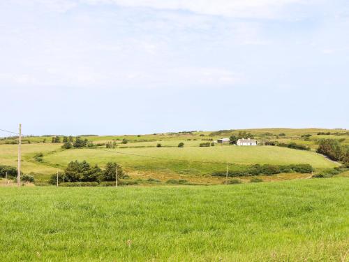 a field of green grass with a house in the distance at Teach Ti in Miltown Malbay