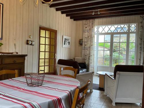 a dining room with a table and chairs and windows at Gite les Flots Bleus in Jullouville-les-Pins