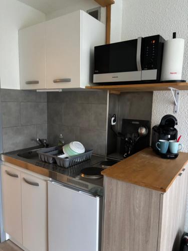 une cuisine avec une cuisinière et un micro-ondes dans l'établissement Studio cabine au pied des pistes, à Modane
