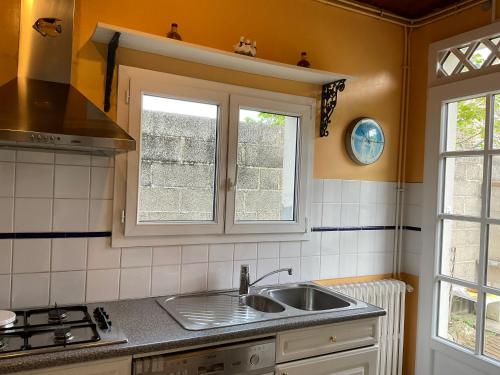 a kitchen with a sink and two windows at Gite les Flots Bleus in Jullouville-les-Pins