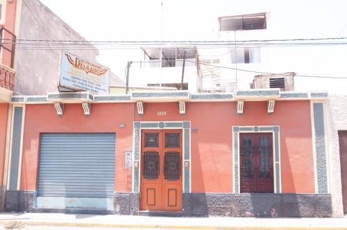 an orange building with two doors on a street at Hab Simple baño compartido Estudiante o Voluntario terraza vista a los Volcanes in Arequipa