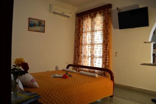 um quarto com uma cama com uma colcha laranja e uma janela em Dimitra Studios em Kastraki