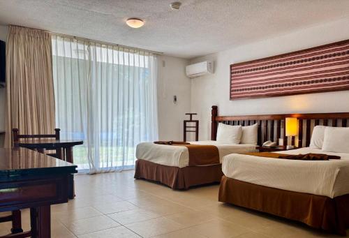 a hotel room with two beds and a piano at Hotel Nututun Palenque in Palenque